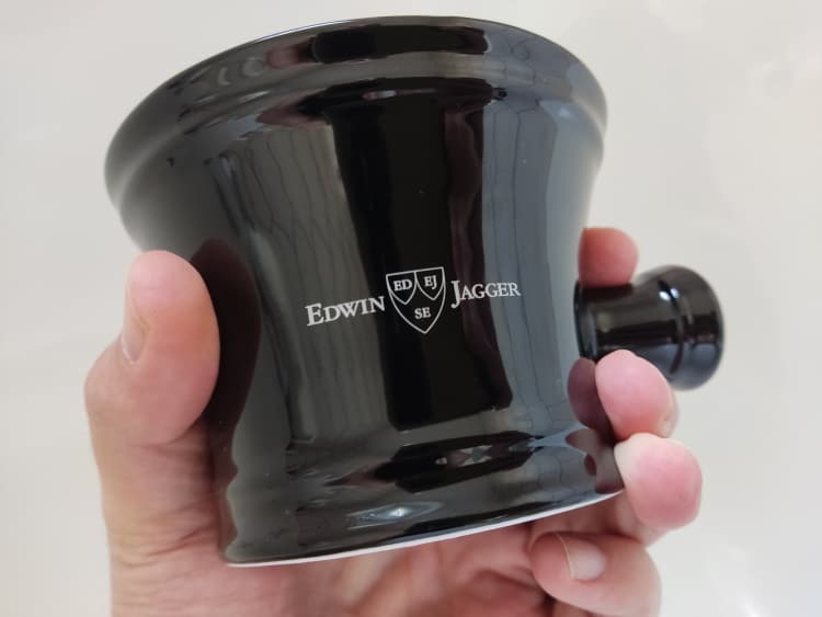 holding an Edwin Jagger Porcelain Black Shaving Bowl with Handle with visible logo