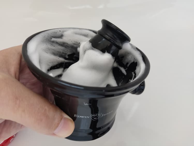 lathering inside a ceramic black shaving bowl