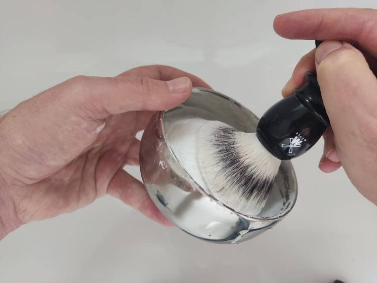lathering shaving soap in metal shaving bowl and with Muhle brush