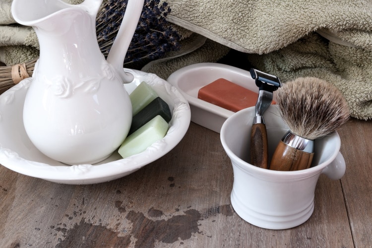 shaving mug with brush and razor on wooden surface