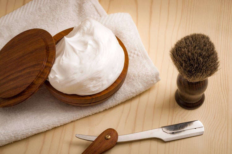 wooden shaving bowl with lather inside and shaving brush and straight razor