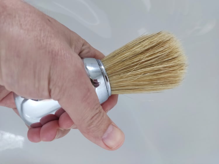 holding the Omega 10048 Professional Shaving Brush to show its size