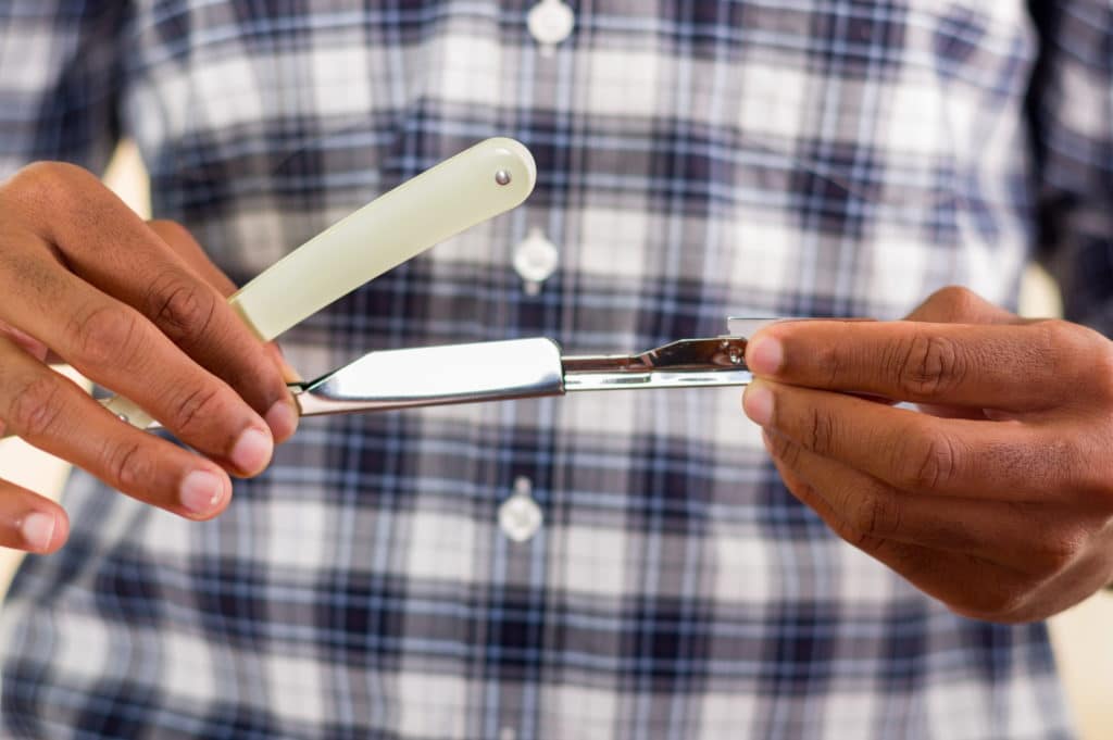 Man holding a shavette razor in his hands
