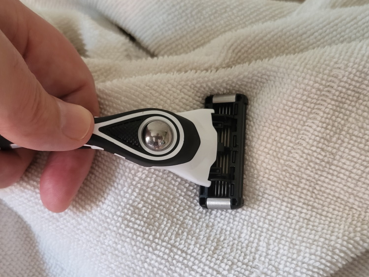 patting a BIC Flex 5 Hybrid blade on a white towel to dry and preserve the blade