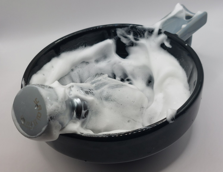 stirling shaving soap lathered in a black shaving bowl with shaving brush