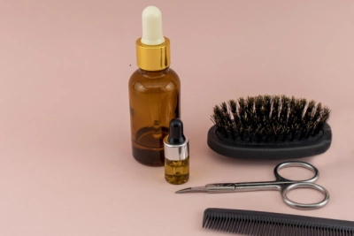 beard oil brush and comb on pink background