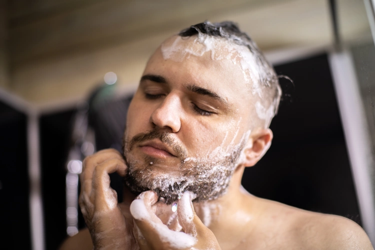 young man washing his hair and beard with shampoo