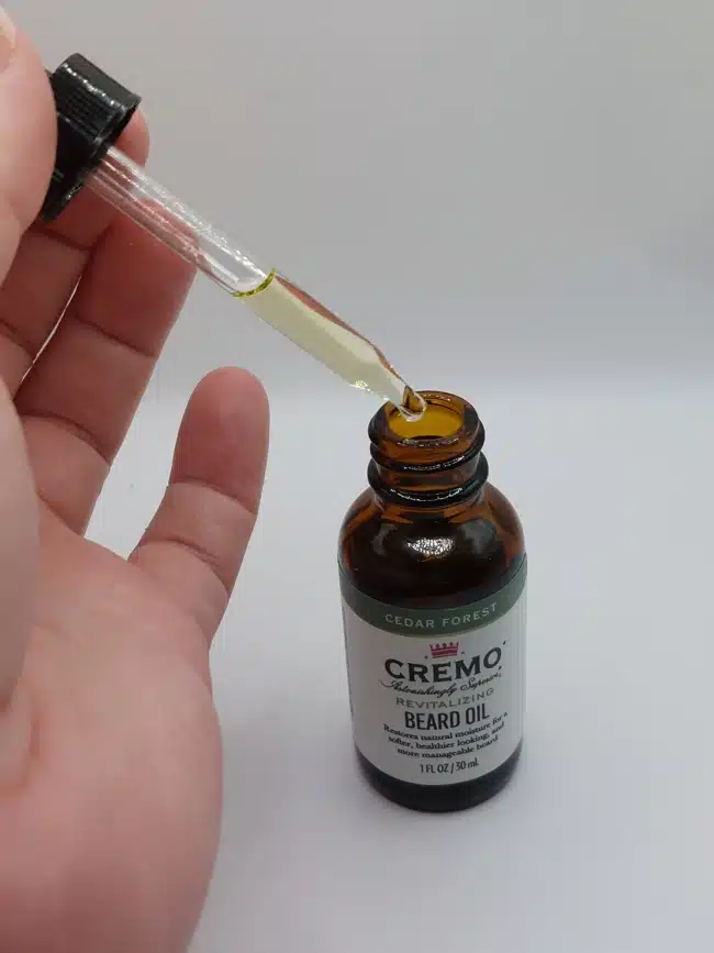 drawing oil from the Cremo Cedar Forest Beard Oil dropper