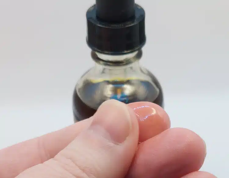 close up of Honest Amish Premium Beard Oil between the fingers to show texture