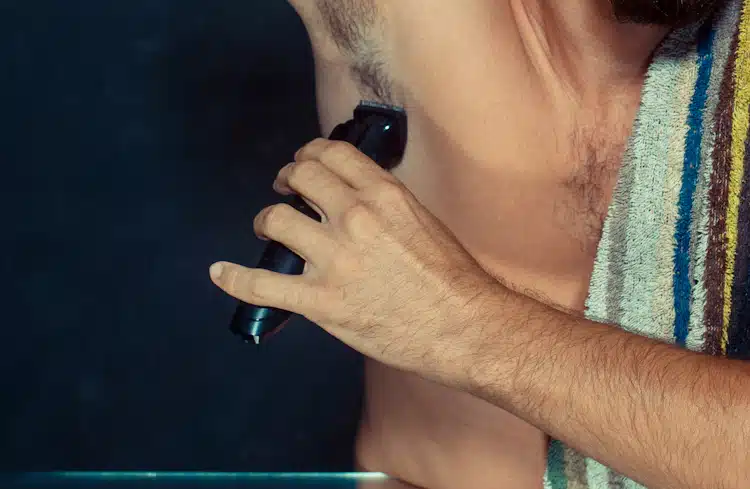 man trimming hairy armpit with electric trimmer