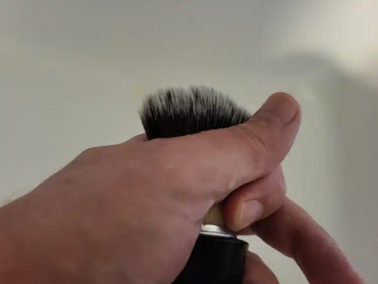 removing by hand excess water from a shaving brush