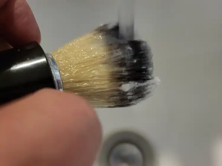 rinsing shaving lather out of a shaving brush under the tap