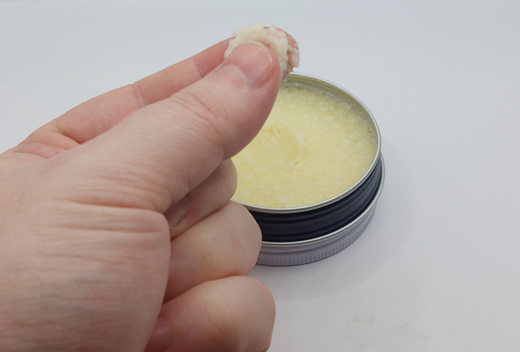 rubbing some Best Damn Beard Balm between a finger and thumb to test texture