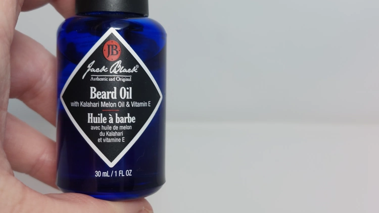 holding Jack Black Beard Oil bottle to display front section and writing