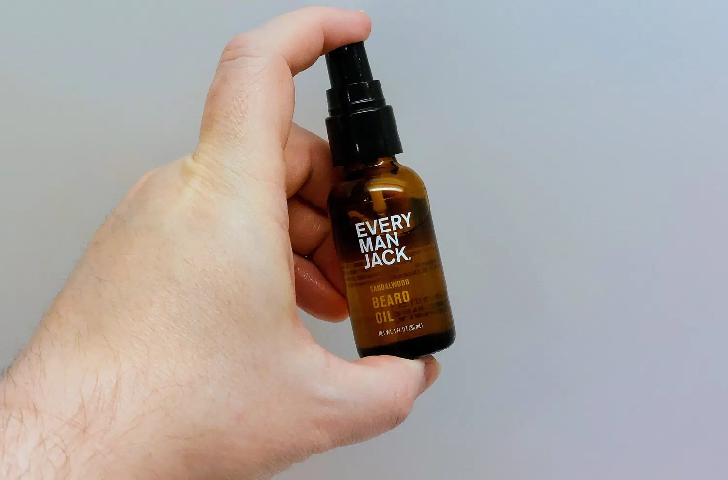 holding a bottle of Every Man Jack Beard Oil bottle between fingers to show how it looks
