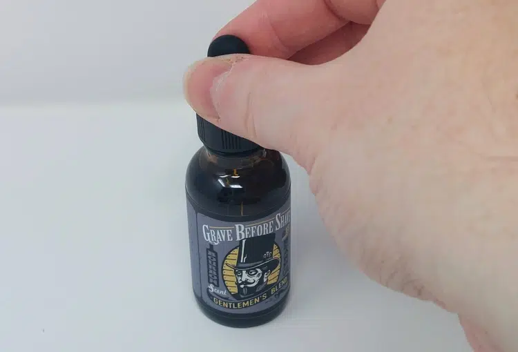 pressing the dropper on the Grave Before Shave Beard Oil bottle