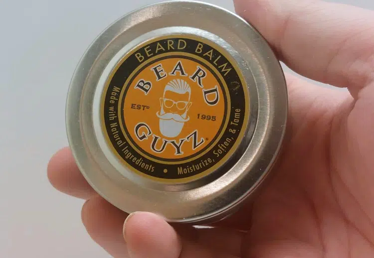 holding a tin of Beard Guyz Beard Balm