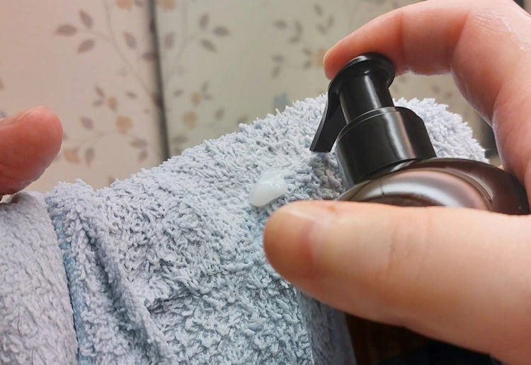 squeezing a small amount of King C. Gillette Beard & Face Wash on a wash cloth ready to use