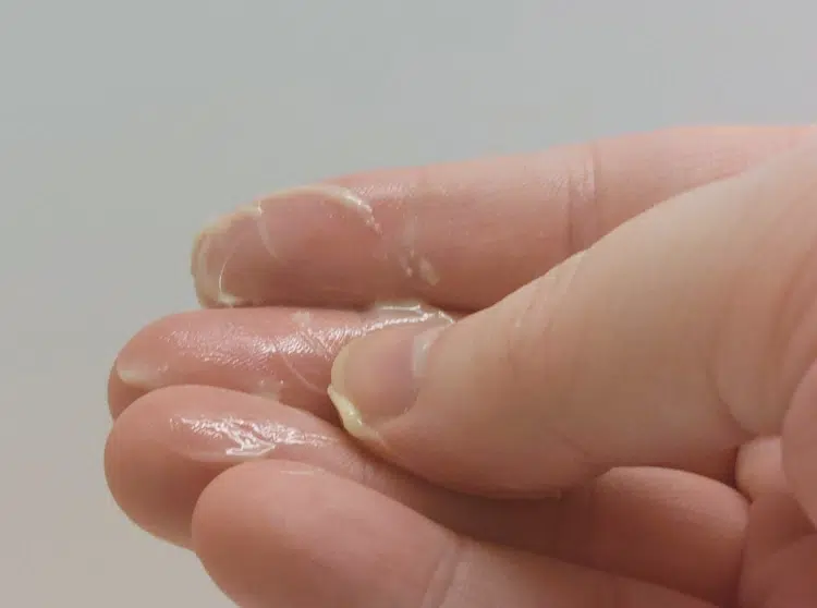 rubbing beard balm between fingers to display its texture