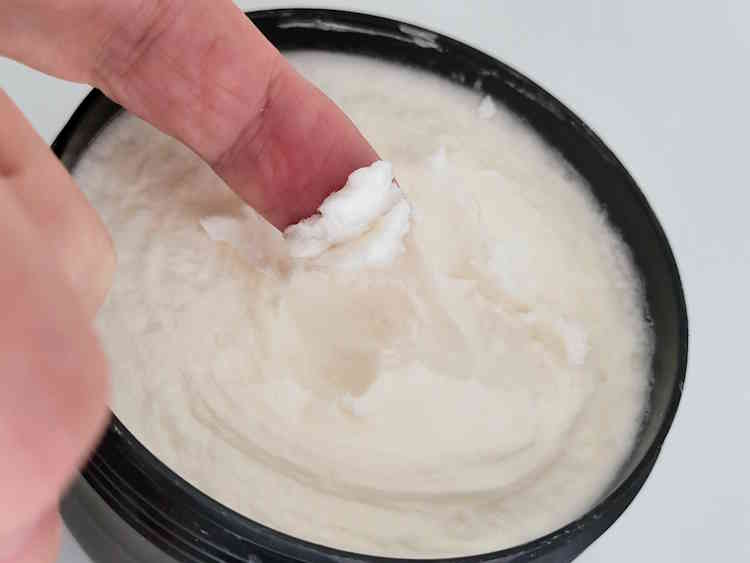 close up of taking a small amount of TOBS Oud Shaving Cream from its tub to use