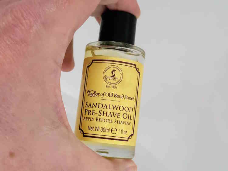 holding a bottle of Taylor of Old Bond Street Sandalwood Pre-Shave Oil to display ist size
