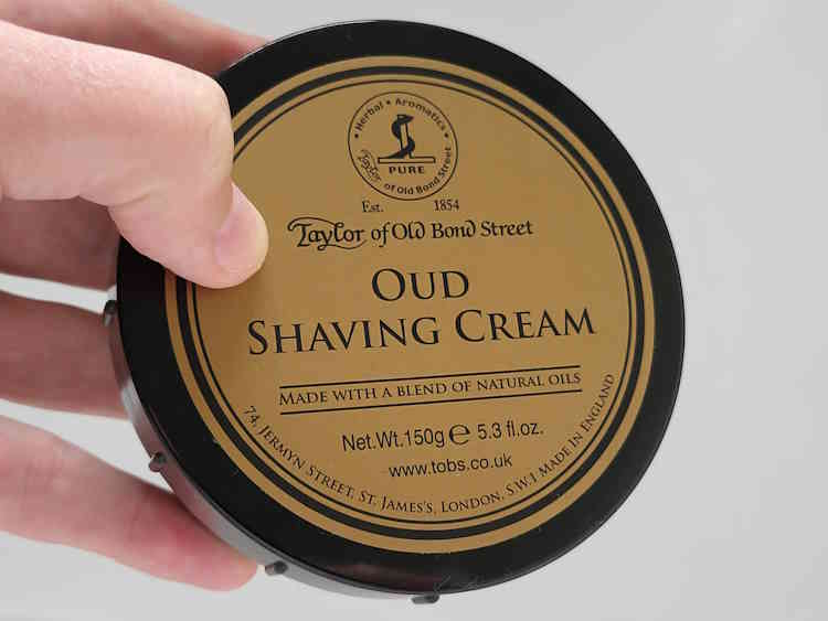 holding a tub of Taylor of Old Bond Street Oud Shaving Cream