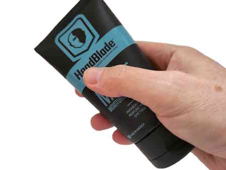 tube of Headblade HeadLube matte held in hand on white background