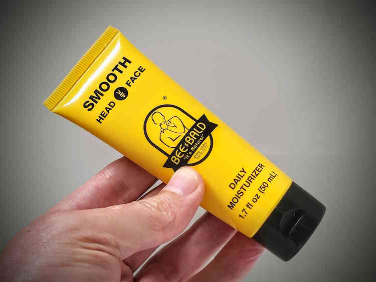Bee Bald Smooth Daily Moisturiser tube held in hand at an angle
