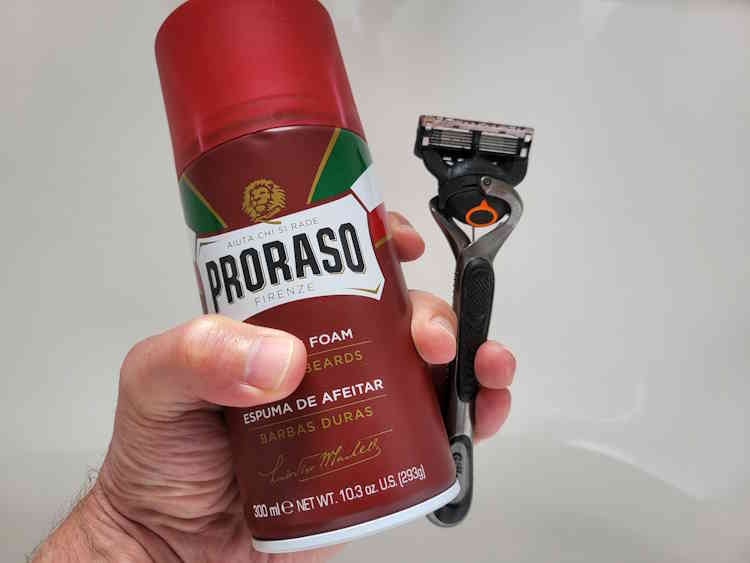 Proraso Red foam can with gillette razor held in the hand together