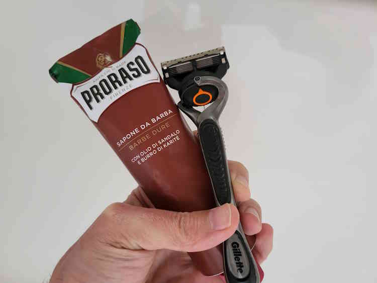 Proraso Red shaving cream tube with gillette razor held in the hand together