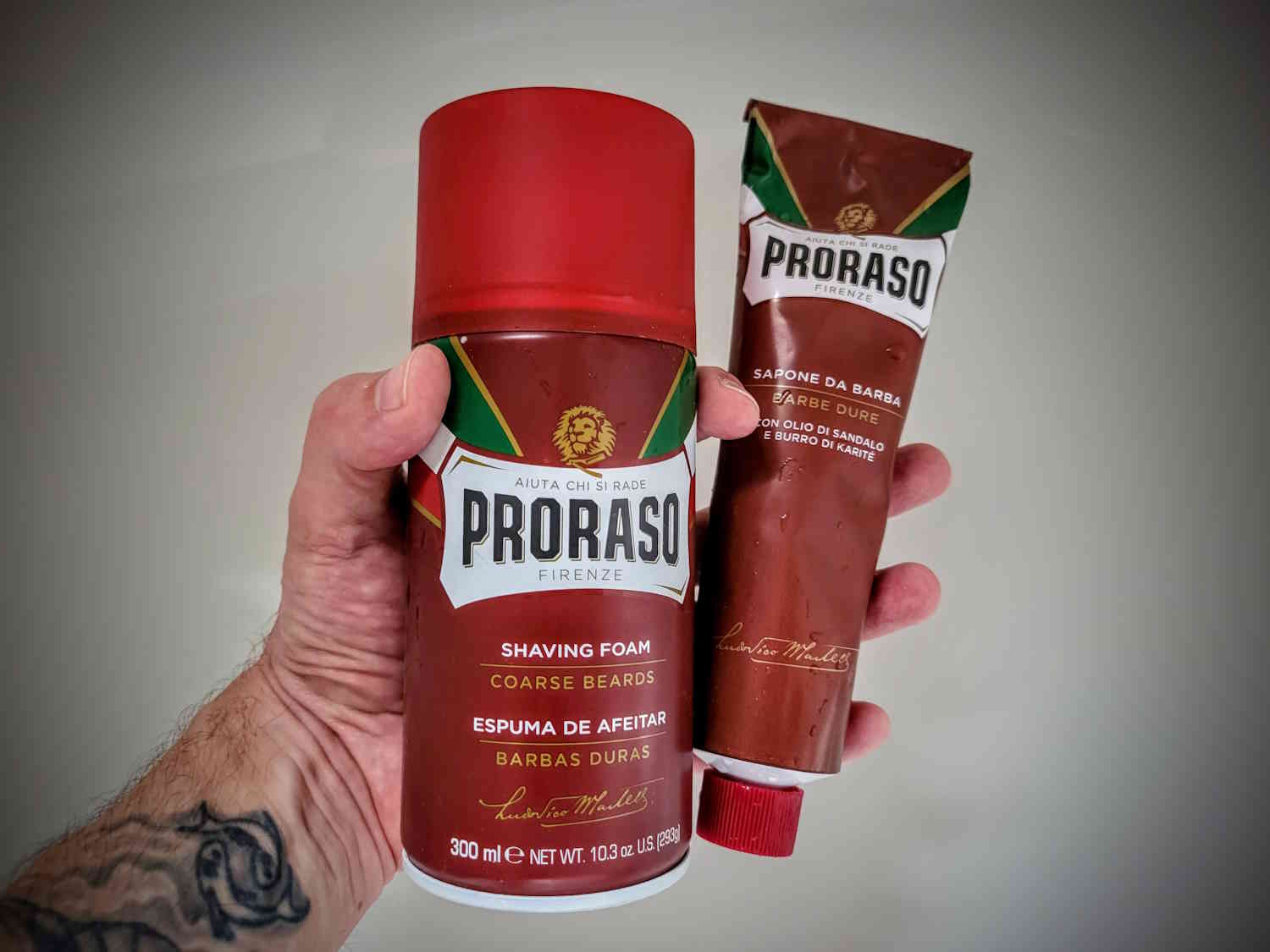 holding Proraso shaving cream tube and Proraso shaving foam can in the hand