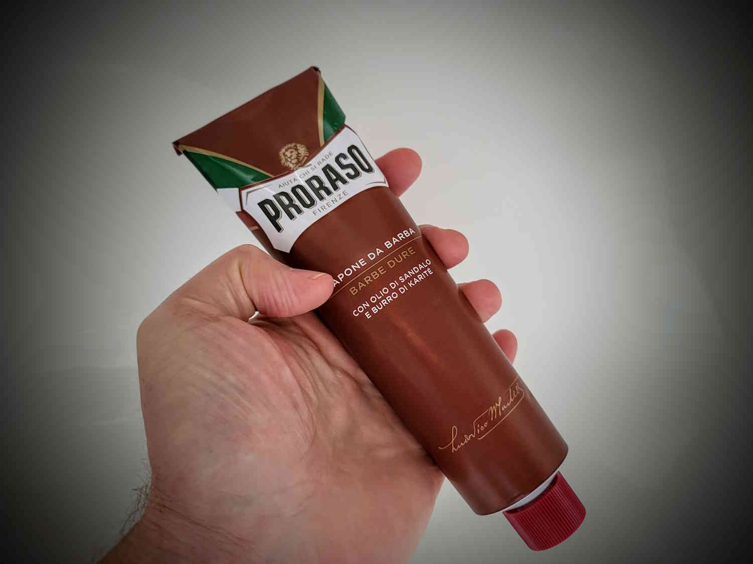 holding a tube of Proraso Red shaving cream in the hand at an angle to display its appearance