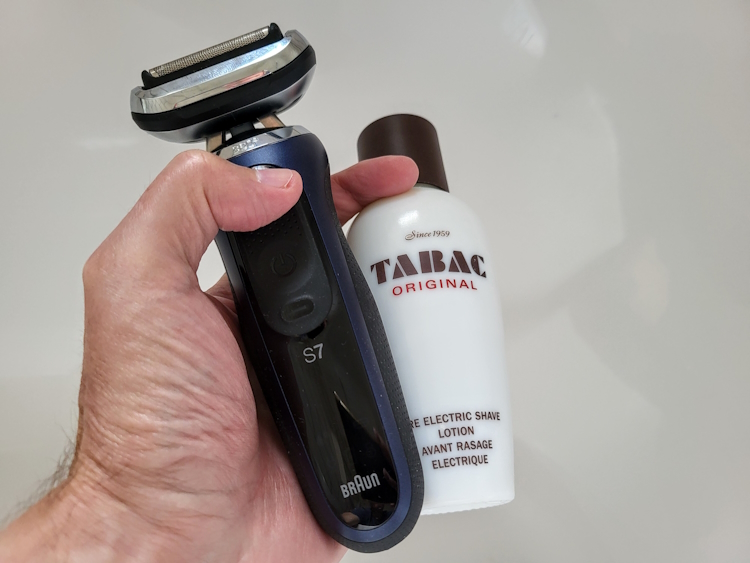 holding a bottle of Tabac Pre-Electric Shave Lotion and Braun Series 7 shaver