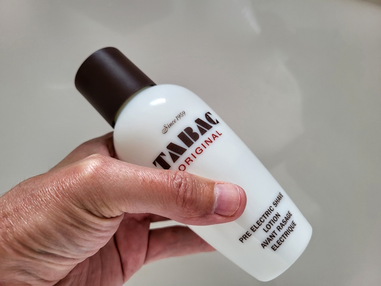 holding a bottle of Tabac Pre-Electric Shave Lotion