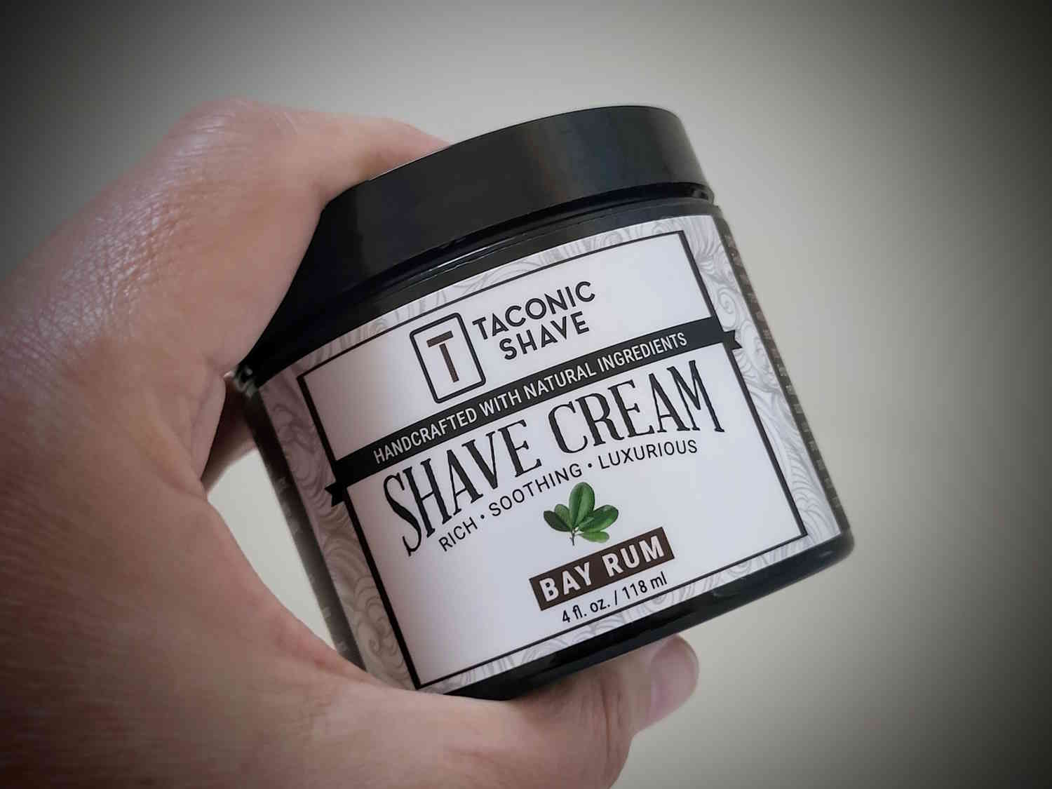 holding a tub of Taconic Bay Rum Shave Cream