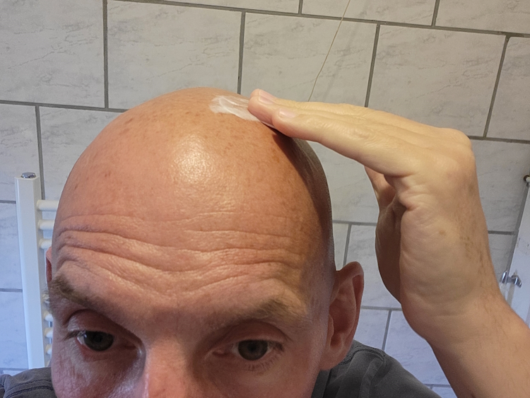 applying a small amount of Bald Boss Face & Scalp Moisturiser on bald head