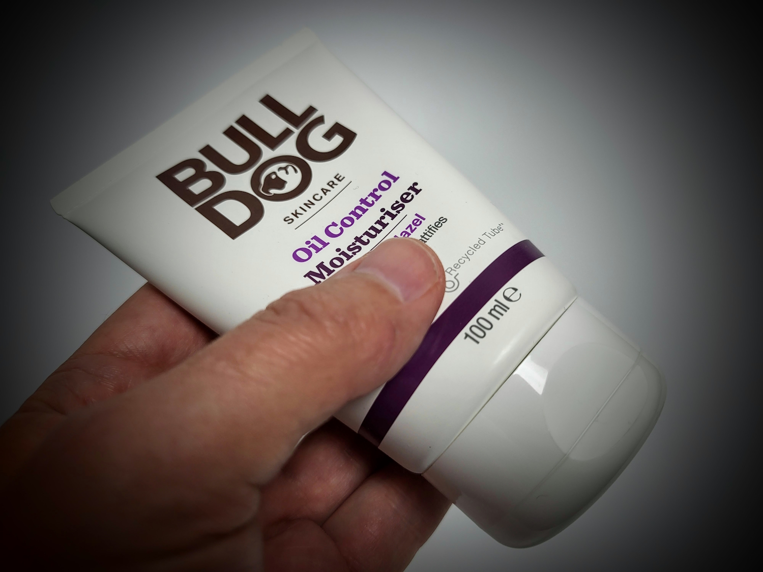 holding a tube of Bulldog Oil Control Moisturiser