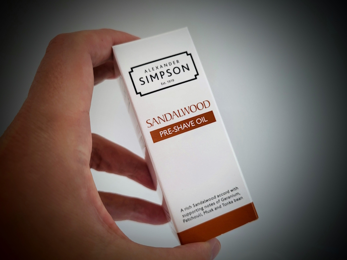 holding Simpson Sandalwood Pre-Shave Oil box with oil bottle inside