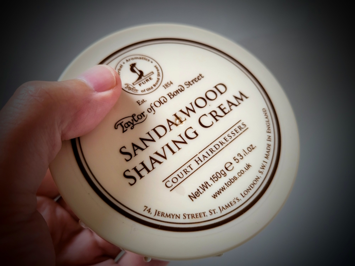 holding a tub of Taylor Of Old Bond Street Sandalwood Shaving Cream