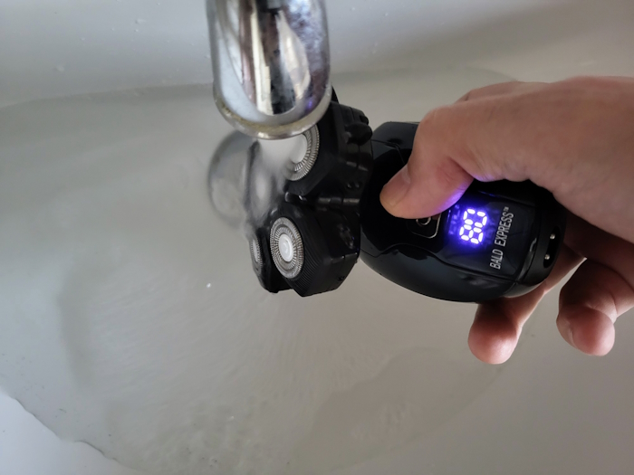 cleaning the Bald Express head shaver under a tap with running warm water