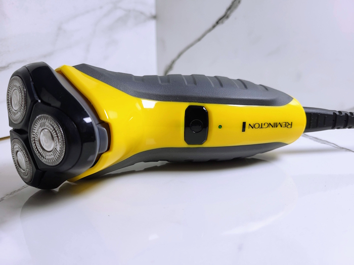Remington Virtually Indestructible shaver laid down with cord attached and chaging