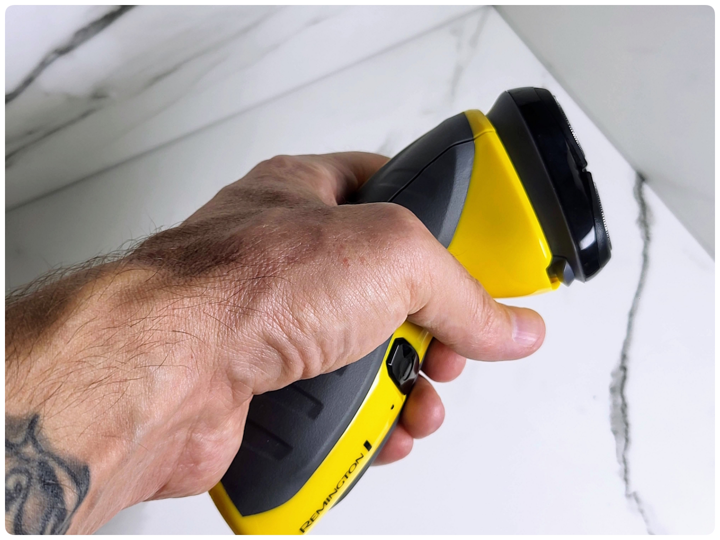 holding Remington Virtually Indestructible shaver to display its ergonomics