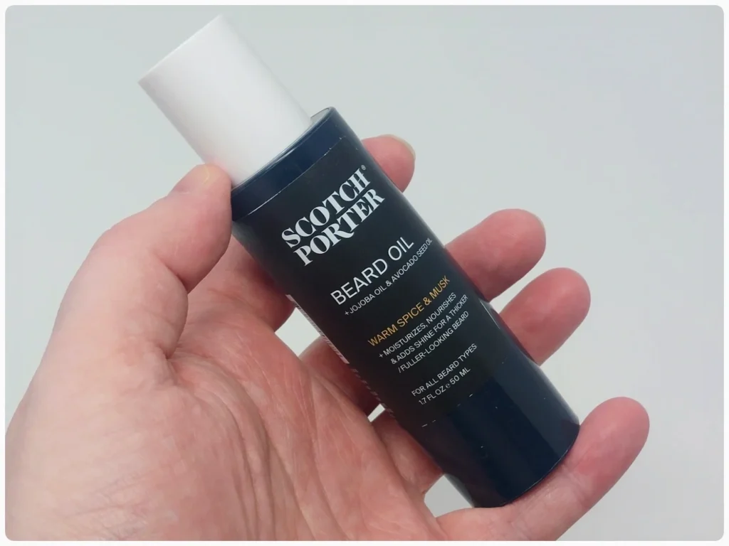 holding a bottle of Scotch Porter Beard Oil at an angle
