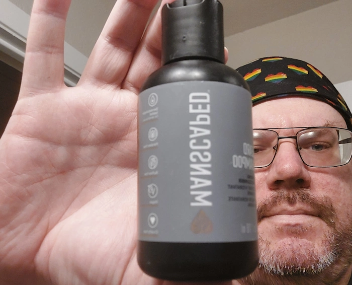 Robert holding a bottle of Manscaped Beard Shampoo between his fingers