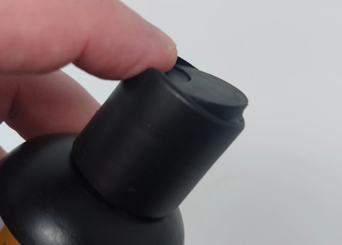 close up of pressing the top cap open on a bottle of Manscaped Beard Shampoo