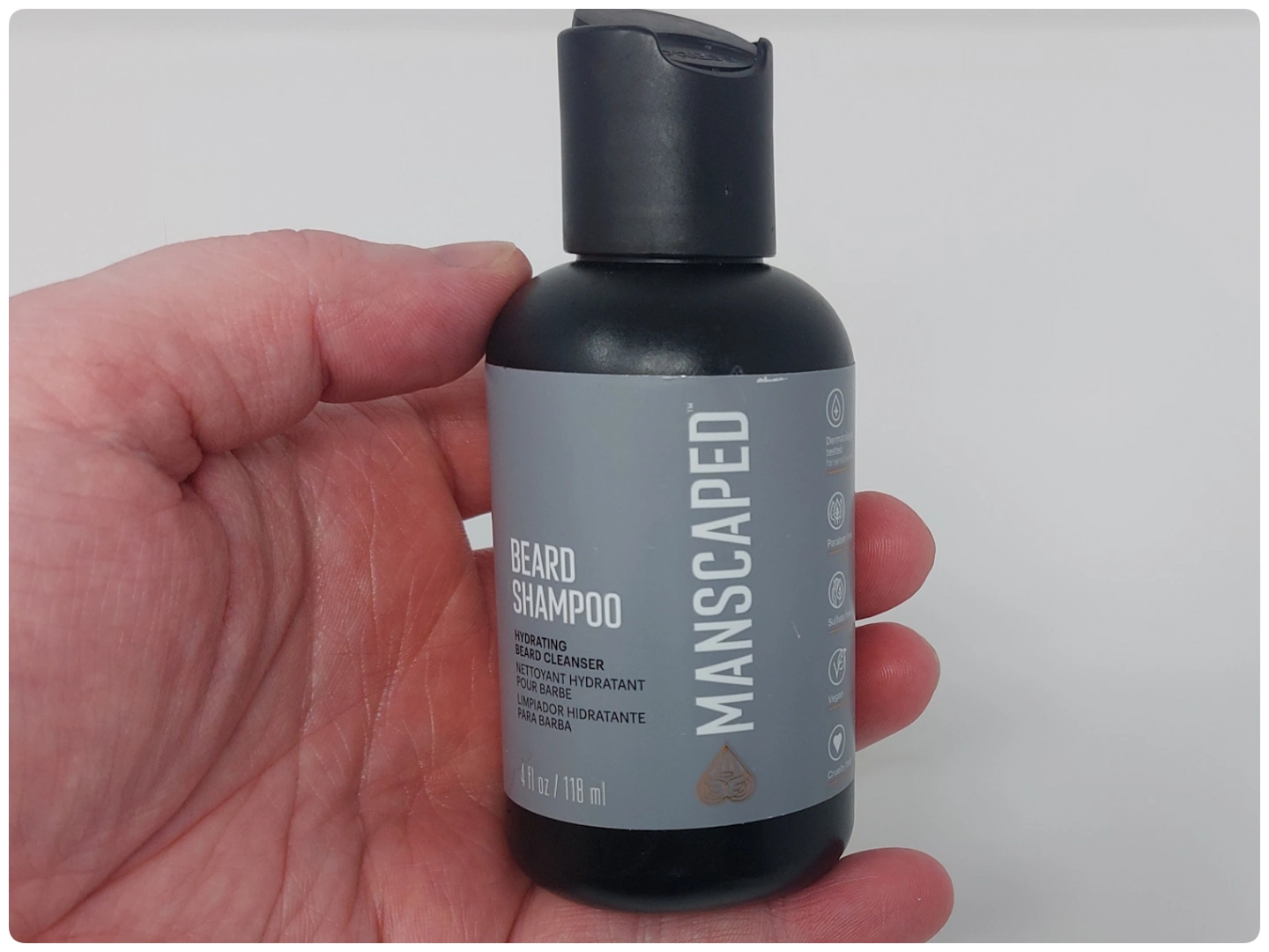 holding a bottle of Manscaped Beard Shampoo