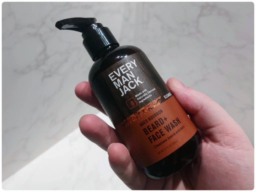 holding a bottle of Every Man Jack Aged Bourbon Beard Wash